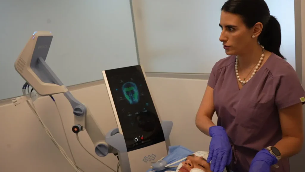 lunares cancerigenos | Clínica de Dermatología Robótica Doctora aplicando Sesión real con la tecnología EMFACE en rostro femenino